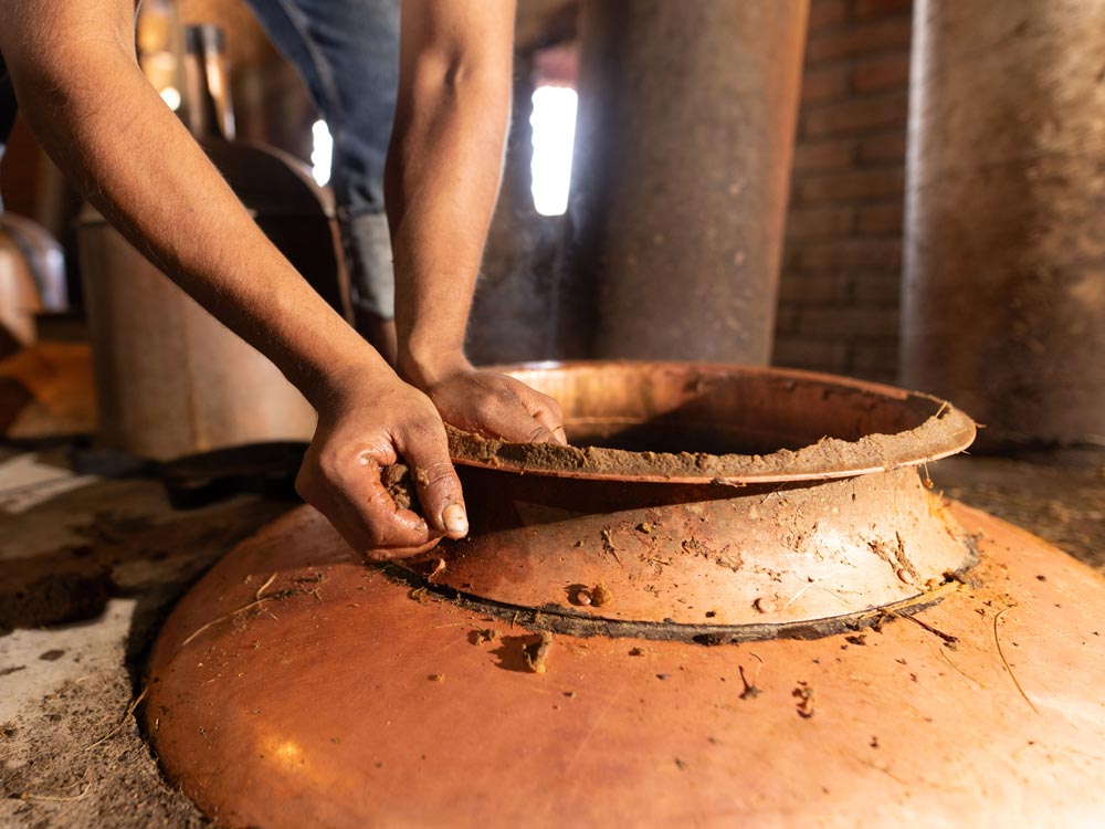 estilación artesanal del mezcal en alambique de cobre, con fuego de leña.