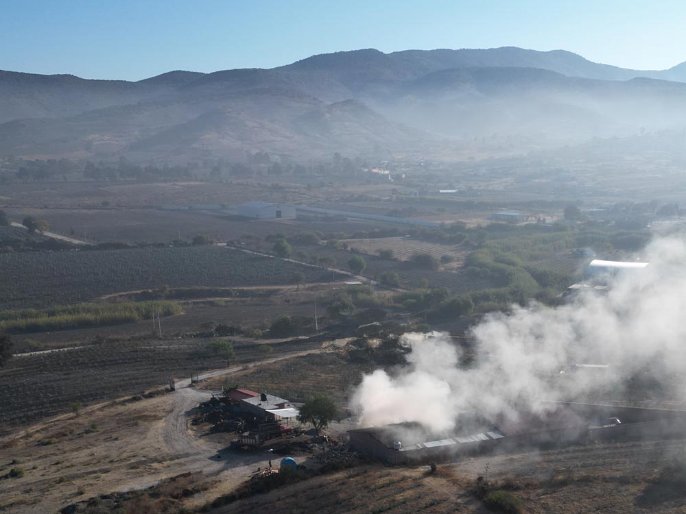 Vista aérea del palenque de Casa Xamu rodeado de sembradíos de agave y montañas.